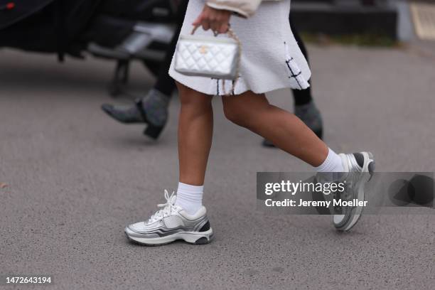 Fashion week guest seen wearing a white dress, a silver bag, white socks and silver and white sneakers before the Chanel show on March 07, 2023 in...