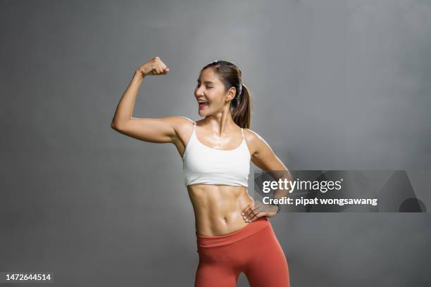 asian woman exercising showing her muscles in the gym, fitness and wellness concept. - asian female bodybuilder stock pictures, royalty-free photos & images