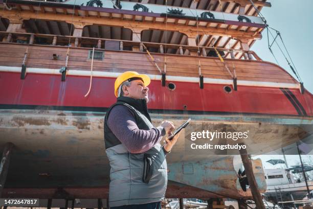 ingenieur mit projekt in einem digitalen tablet arbeitet in einem shypyard - boat helm stock-fotos und bilder