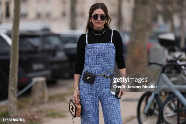 Paola Alberdi seen wearing a blue tweed jumpsuit, a black turtle neck sweater, a black belt bag and a black and beige bag by Chanel, black shades and...