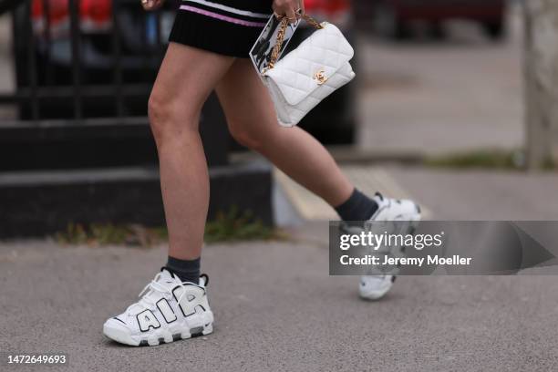 Charlotte Groeneveld seen wearing black and white Nike Air shoes, a matching knit set with a cardigan and a mini skirt, two white leather bags and...