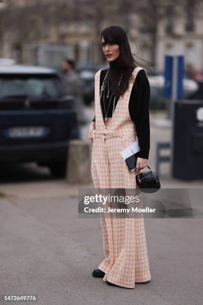 Leia Sfez seen wearing checked dungarees, a black knit sweater, black leather pants and black boots before the Chanel show on March 07, 2023 in...