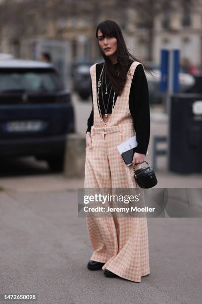 Leia Sfez seen wearing checked dungarees, a black knit sweater, black leather pants and black boots before the Chanel show on March 07, 2023 in...