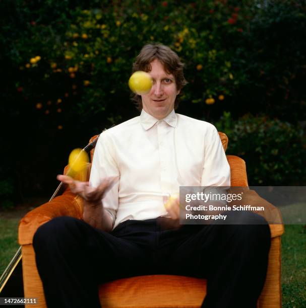 Musician T-Bone Burnett juggles lemons while seated in a plush orange velvet chair flanked by his guitar outside in Los Angeles in 1982.