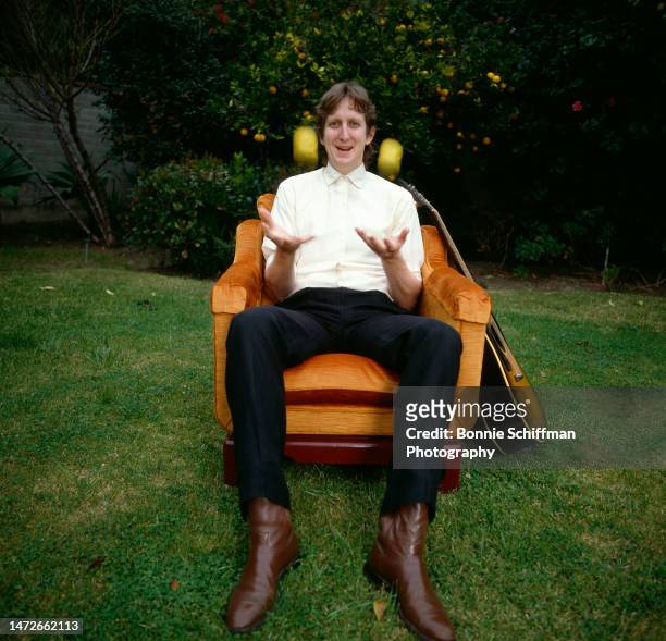 Musician T-Bone Burnett juggles lemons while seated in a plush orange velvet chair flanked by his guitar outside in Los Angeles in 1982.