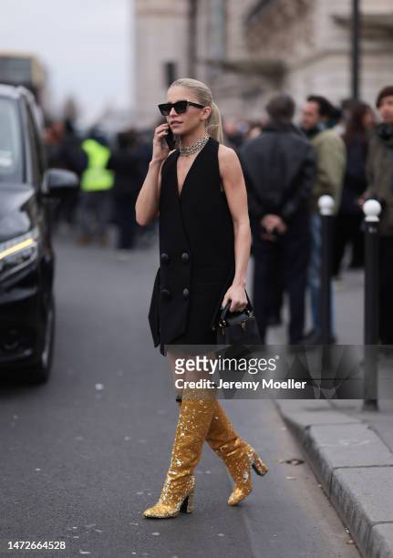 Caro Daur is seen wearing a black oversized blazer vest and golden shimmery high heel boots outside the Louis Vuitton Show during Paris Fashion Week...