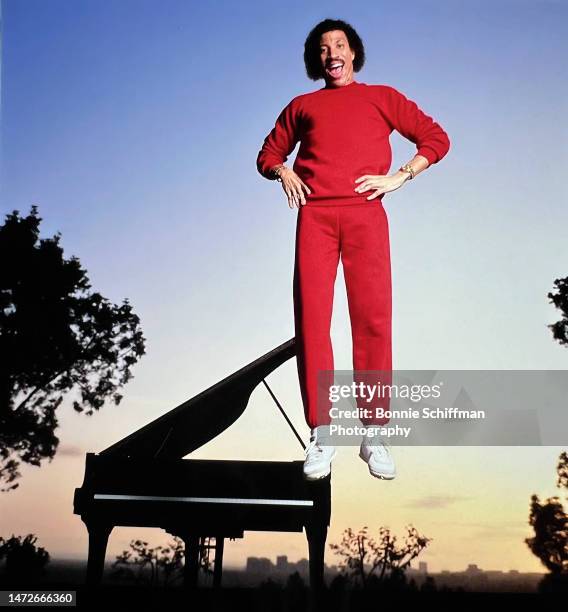 Musician Lionel Richie is captured mid-jump in front of a piano and a sunset in Los Angeles in 1983.