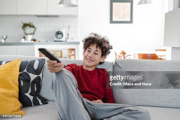 cute teenage boy watching tv in the living room - 12 year old cute boys stock pictures, royalty-free photos & images