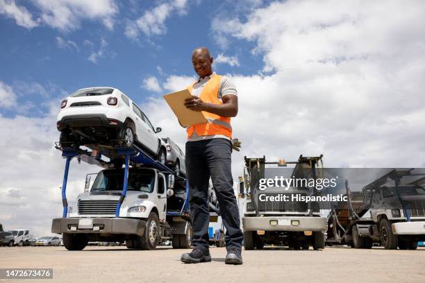 hombre trabajando en un almacén de distribución supervisando el envío de automóviles - carrying fotografías e imágenes de stock