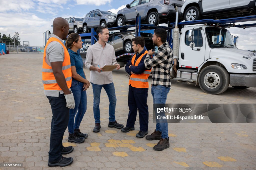 Boss talking to a group of workers transporting cars