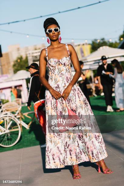 Guest is seen wearing an floral maxi dress, white sunglasses, pink shoes and pink handbag outside the Suit Up Runway at Melbourne Fashion Festival on...