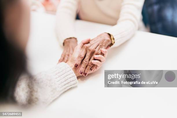 unrecognizable cropped image of woman holding hands with her mother - kin in de hand stock-fotos und bilder