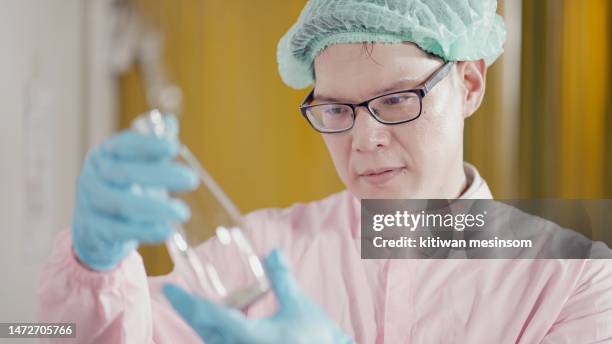 manager or engineers or chief leader of production line wearing hairnet and sterile clothing and gloves, checking quality of bottle for product of machine filling fruit juices at manufacturing plant. concept of factory, industry. - chief scientist stock pictures, royalty-free photos & images