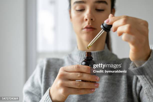 mulher que segura as gotas de óleo de cbd - cannabis oil - fotografias e filmes do acervo