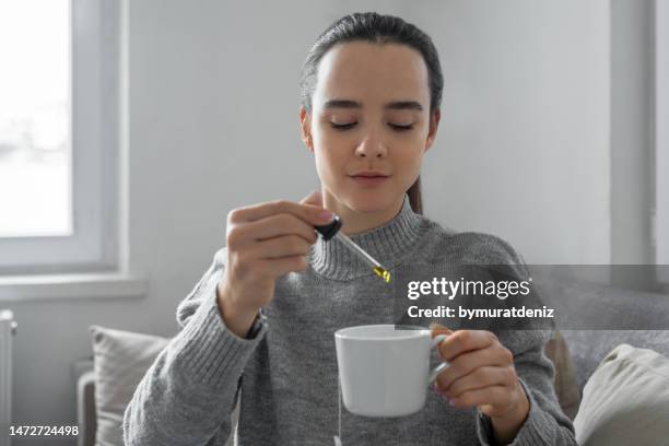 woman drinks tea with drops of cannabis oil for stress relief - cbd oil stock pictures, royalty-free photos & images