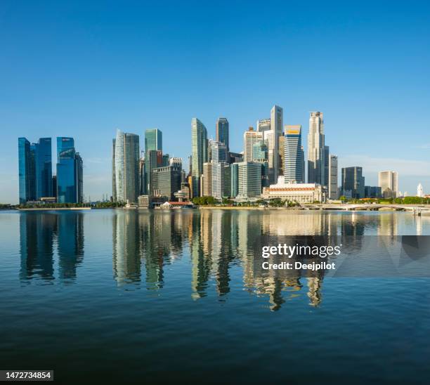 view across marina bay towards the singapore city skyline at sunrise - singapore skyline stockfoto's en -beelden