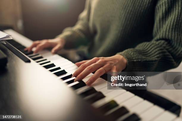 teenage girl practicing piano at home - pianist stockfoto's en -beelden
