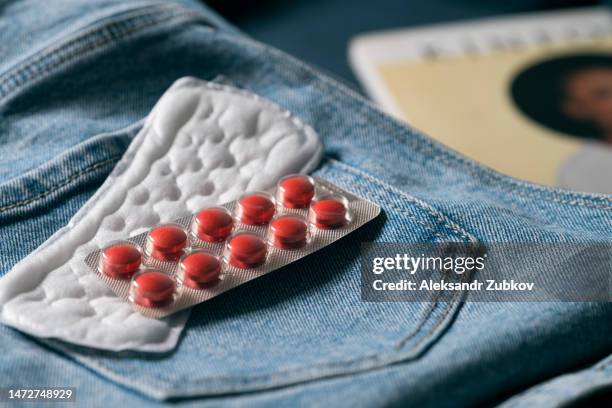 sanitary napkins and pads for the menstrual cycle. pills, medications on jeans. when going on a trip, take your personal belongings with you. the concept of critical days, menstruation. gynecology. healthcare and medicine. women's problems and diseases. - period blood foto e immagini stock