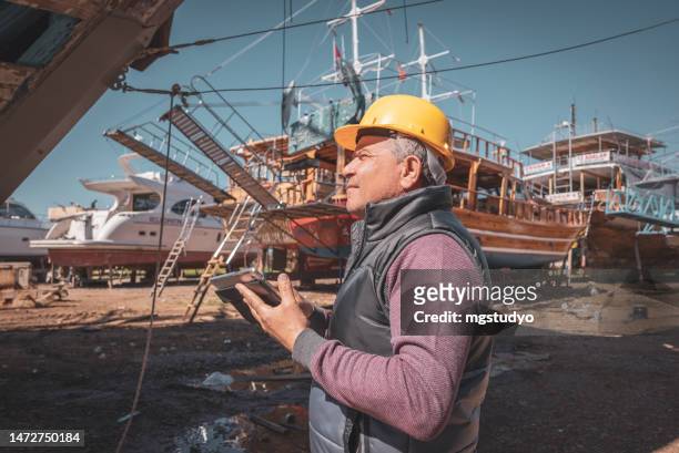 ausgebildeter mechaniker, der motorboote auf der werft überprüft - shipyard stock-fotos und bilder