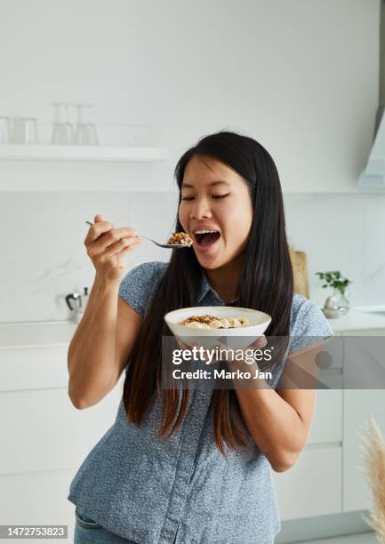 happy woman eating a healthy breakfast - eating cereal stock pictures, royalty-free photos & images