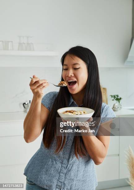 happy woman eating a healthy breakfast - adult eating cereal stock pictures, royalty-free photos & images