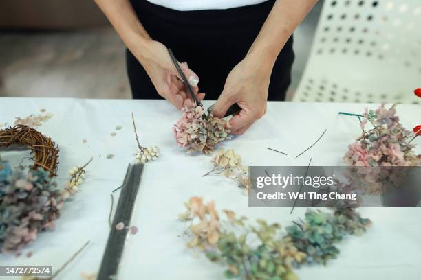 a female florist is making a wreath with hydrangeas - flower crown stock pictures, royalty-free photos & images