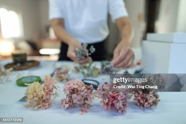 a female florist is making a wreath with hydrangeas - hydrangea lifestyle stockfoto's en -beelden