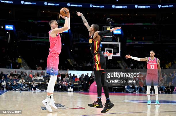 Kristaps Porzingis of the Washington Wizards shoots the ball against Dejounte Murray of the Atlanta Hawks at Capital One Arena on March 08, 2023 in...