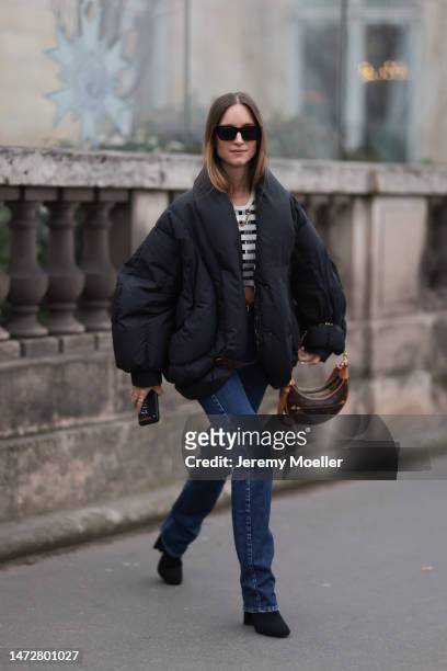 Charlotte Groeneveld is seen wearing black puffer jacket, bag with Louis Vuitton logo print, navy jeans, white cropped top outside the Louis Vuitton...