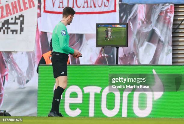 Referee Matthias Jollenbeck checks the Video Assistant Referee screen before giving a penalty to Borussia Moenchengladbach during the Bundesliga...
