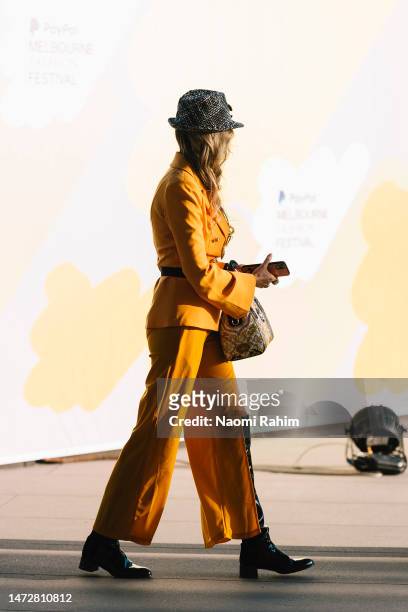 Guest is seen wearing a yellow suit, Hermès belt and Versace handbag outside the Closing Runway at Melbourne Fashion Festival on March 11, 2023 in...