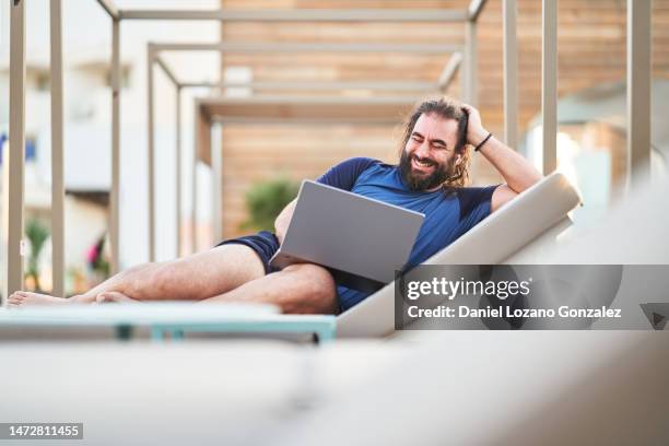 relaxed man during a video call with a laptop outdoors - business social gathering poolside stock pictures, royalty-free photos & images