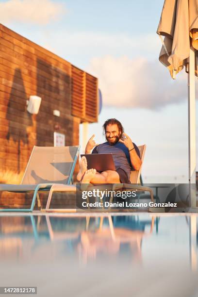 man gesturing happily during a video call on a pool - hotel confirmation stock pictures, royalty-free photos & images