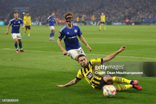 Raphael Guerreiro of Borussia Dortmund slides in an attempt to keep the ball in whilst under pressure from Cedric Brunner of FC Schalke 04 during the...