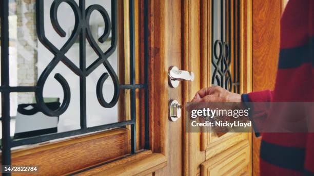 senior man opening the front door of his vacation rental - sleutel beveiligingsapparatuur stockfoto's en -beelden