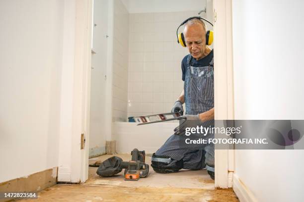 senior caucasian man doing construction renovation indoors - handyman stockfoto's en -beelden