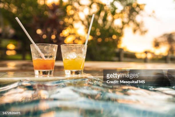 gläser getränke am pool - drinkwater kante stock-fotos und bilder