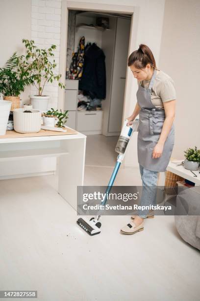 woman after transplanting flowers vacuuming the floor of the house - grüner handschuh stock-fotos und bilder