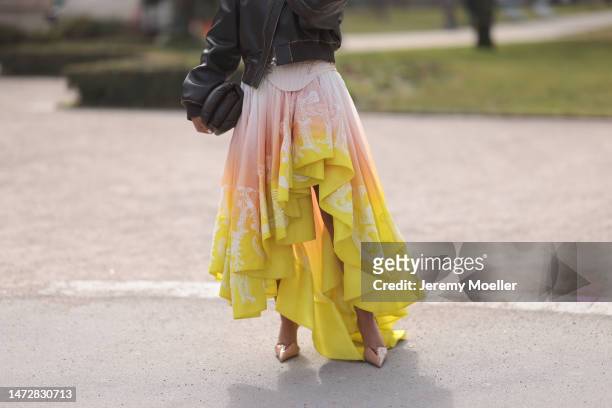 Oumayma Elboumeshouli is seen wearing a dark grey leather jacket, a matching bag, a pink and yellow tulle mullet dress and high heels before the...