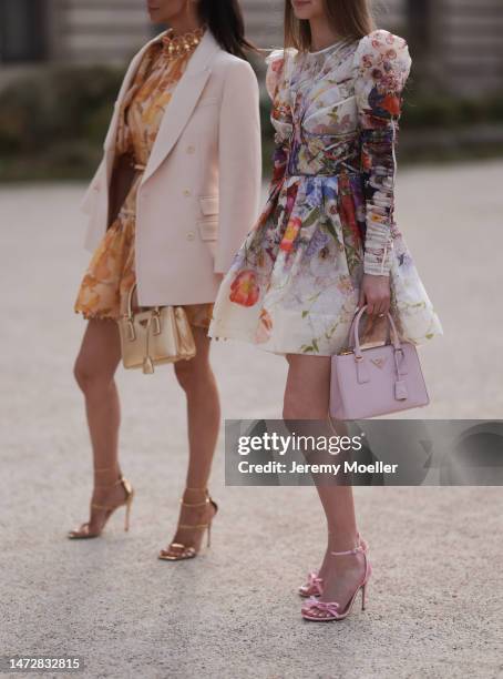 Hannah Collins is seen wearing a light purple Prada galleria bag, a colourful printed dress and high heels and Amy Collins is seen wearing a golden...