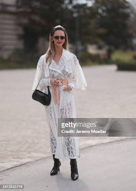Fashion week guest seen wearing a white semi sheer dress, a black bag, black boots, a belt and sunglasses before the Zimmermann show on March 06,...