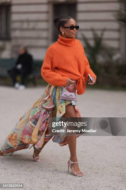 Ellie Delphine is seen wearing an orange turtleneck, a colourful skirt, high heels, dark sunglasses and a mini bag by Mach & Mach before the...