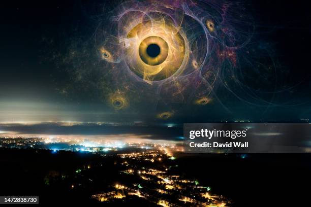 a science fiction concept. a glowing alien eye monster. floating in the sky above a city at night. - town of the gods stock pictures, royalty-free photos & images