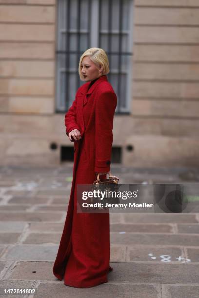 Fashion Week guest is seen wearing a long red coat and Louis Vuitton brown monogram handbag and golden Louis Vuitton earrings outside the Louis...