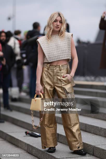 Fashion Week guest is seen wearing a beige cropped top, golden cargo pants and yellow mini Louis Vuitton handbag with golden chain details and black...