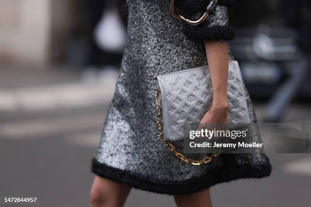 Fashion Week guest is seen wearing a silver and black wool with wavy large borders and cut-out shoulders Louis Vuitton dress, a grey shiny leather...