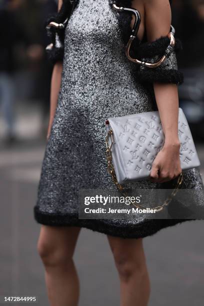 Fashion Week guest is seen wearing a silver and black wool with wavy large borders and cut-out shoulders Louis Vuitton dress, a grey shiny leather...