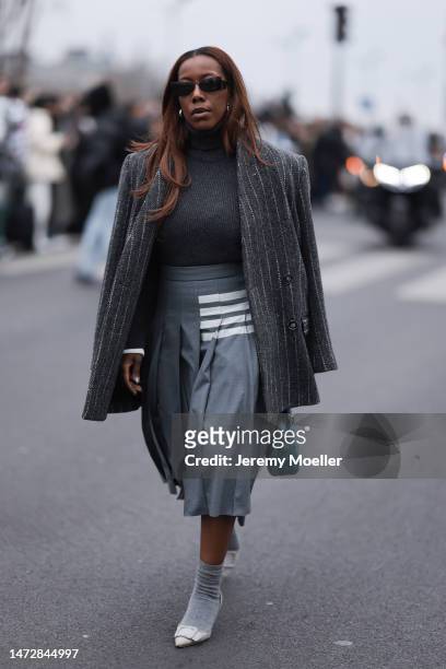 Fashion Week guest is seen wearing a grey turtleneck, grey and white stripped blazer, grey skirt and grey socks and heels and black sunglasses...