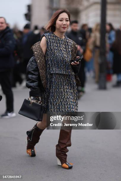 Fashion Week guest is seen wearing a two piece golden and blue outfit, top and skirt, and brown and white and black leather boots, black leather...