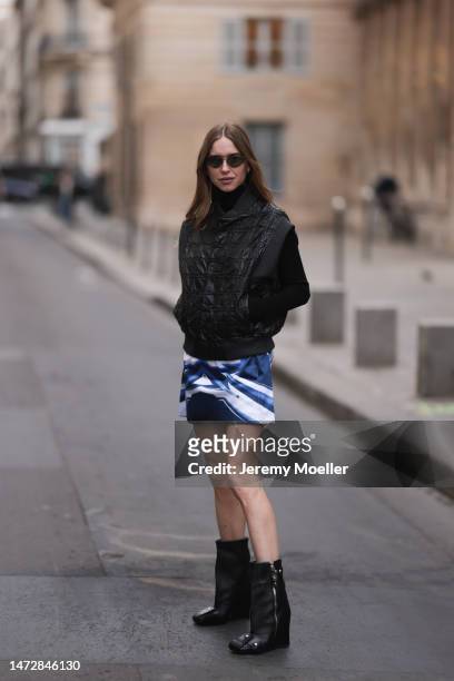 Fashion Week guest seen wearing a black jacket, blue and white mini skirt and black boots and sunglasses outside the Louis Vuitton show during Paris...